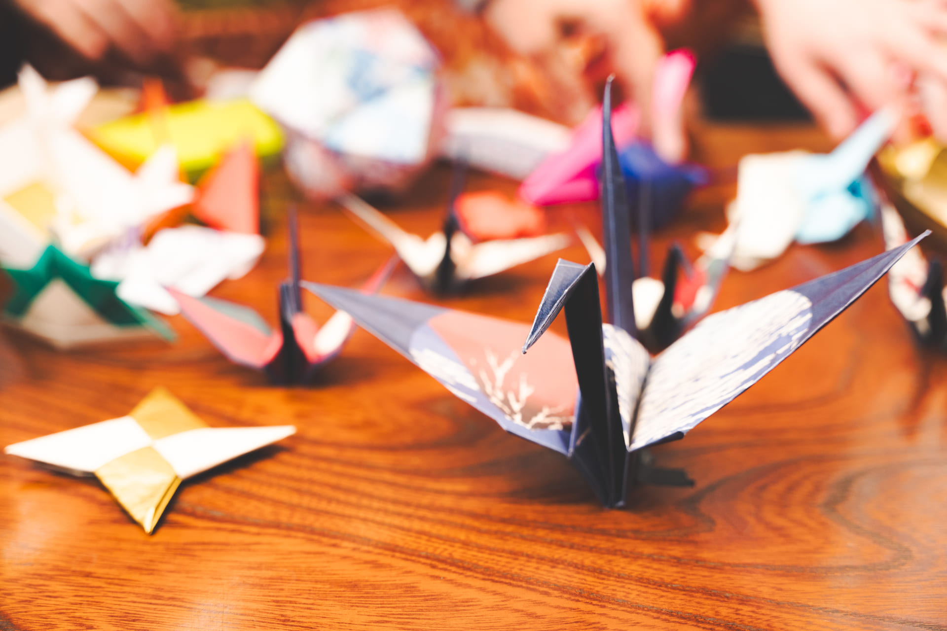 Japanese Cultural Experiences at Kyoto Abeya. Close-up of assorted colorful origami figures on a wooden table, including a prominently featured blue crane.