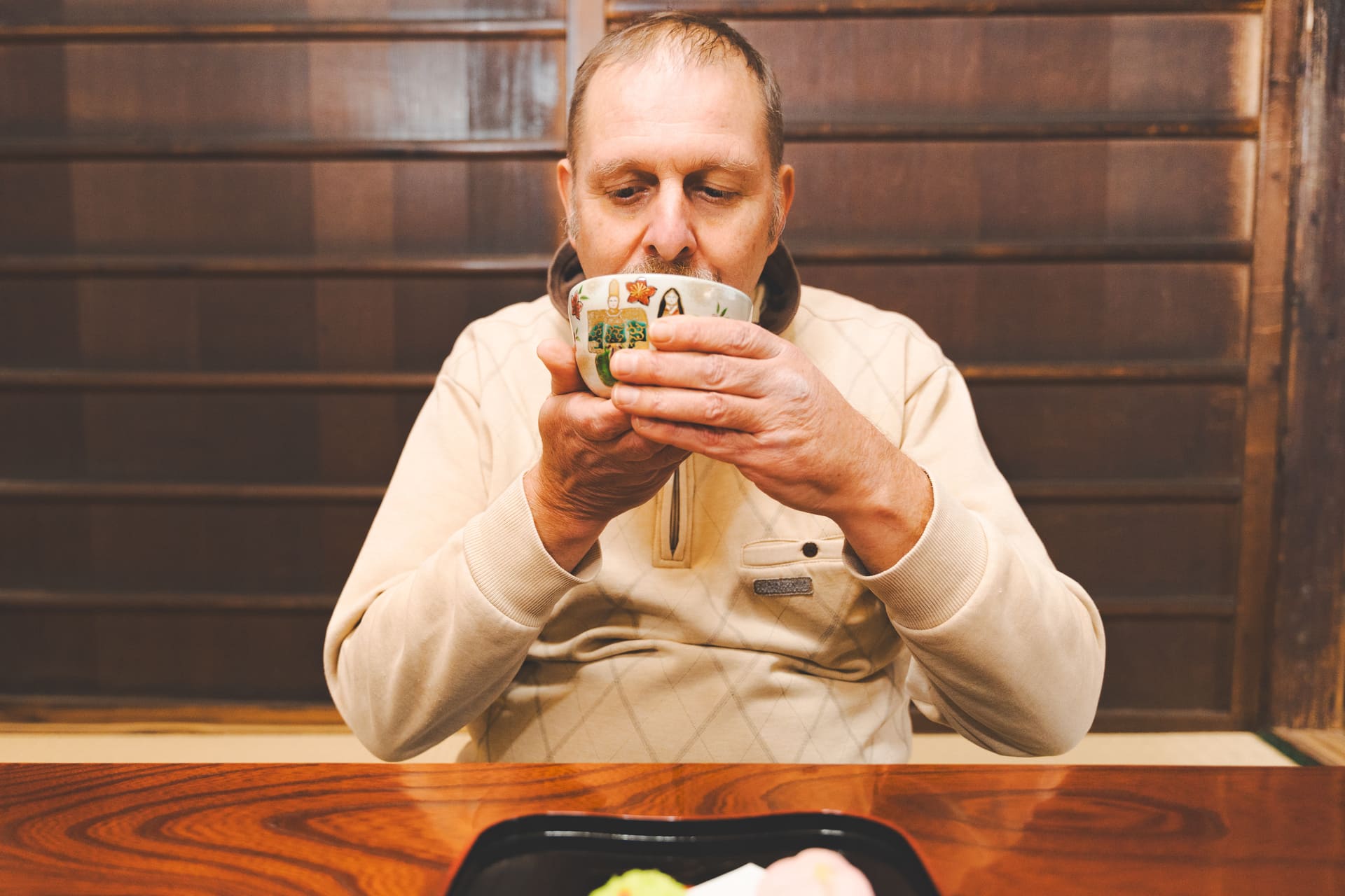 Japanese Cultural Experiences at Kyoto Abeya. A man wearing a sweater is having Japanese green tea with Japanese sweets in front of him.